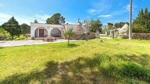 A house with a stone facade, a small garden, and a clear blue sky.