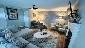 A living room with a sofa, armchairs, a coffee table, a fireplace, and a ceiling fan. - El Rancho Powell (Goldsboro)