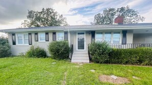 A single-story house with a front porch, a small front yard, and a brick chimney. - El Rancho Powell (Goldsboro)