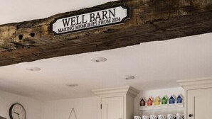 A well-appointed kitchen with a round table, white cabinetry, and a rustic wooden beam above. - A beautiful barn conversion in the charming village of Langham (Langham)
