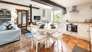 A modern kitchen with white cabinets, a round dining table, and a built-in oven. - A beautiful barn conversion in the charming village of Langham (Langham)