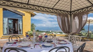 An outdoor dining setup with a table set for four, overlooking a scenic view. - My Rental Homes - Villa delle Rose with private pool, barbeque and air conditioning (Serravalle Pistoiese)