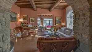 A cozy living room with a piano, a sofa, and a dining area with a table and chairs. - My Rental Homes - Villa delle Rose with private pool, barbeque and air conditioning (Serravalle Pistoiese)