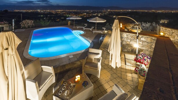 A rooftop pool area with lounge chairs, a hot tub, and a stone wall. - My Rental Homes - Villa delle Rose with private pool, barbeque and air conditioning (Serravalle Pistoiese)