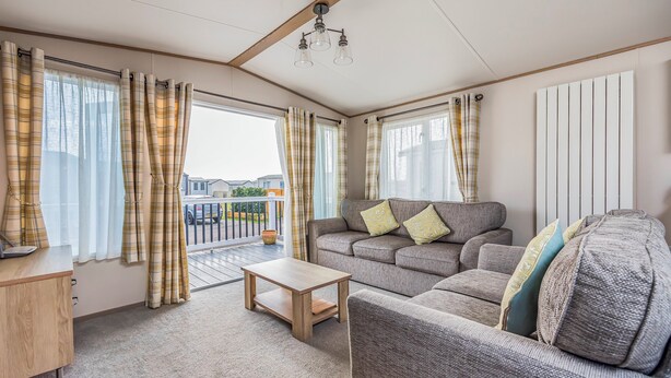 A cozy living room with a sofa, a coffee table, and curtains. - Charming Home in Lakeside Park - Pass The Keys (Chichester)