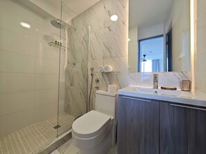 Un baño moderno con cabina de ducha de vidrio, un inodoro y un tocador con espejo.