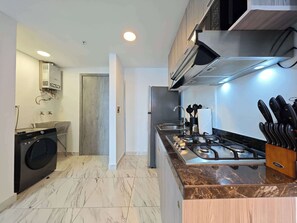 A modern kitchen with a built-in washer, a gas stove, and a stainless steel range hood. - w* | Sunlit 1BR on Avenida Balboa w/ Pool (Panamá)