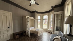 Una habitació amb un llit, una panxa, un sofà i un ventilador de sostre.