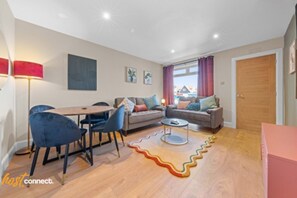A modern living room with a dining area, a sofa set, a coffee table, and a patterned rug. - Modern 2BR in Dunfermline | Sleeps 4 (Cairneyhill)