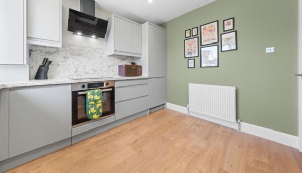 A kitchen with a built-in oven, a microwave, and a gas stove. - Modern 2BR in Dunfermline | Sleeps 4 (Cairneyhill)