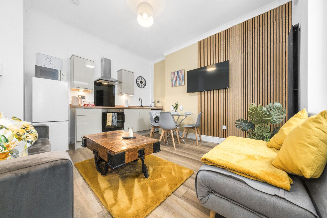 Spacious and comfortable living room featuring a cozy 5-seater sofa, a TV for entertainment, and a stylish coffee table – the perfect space to relax and unwind.