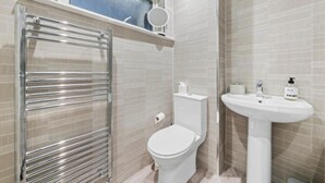 Een badkamer met een toilet, een wastafel en een handdoekhouder.