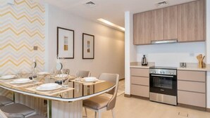 A modern kitchen with a built-in oven, a dining area with a glass table, and a zigzag patterned wall.