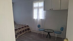 A small room with a bed, two chairs, a table, and a window with curtains. - Fair View Garden #2 (By-BLR) (Fair View)