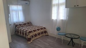 A bedroom with a bed, a chair, a small table, and a wardrobe. - Fair View Garden #2 (By-BLR) (Fair View)