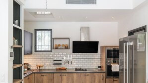A modern kitchen with wood cabinets, a stainless steel refrigerator, and a built-in oven. - Upstays Pool 200m² Villa Near Beach (Cannes)