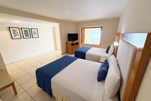 A hotel room with two beds, a TV, a window, and artwork on the wall. - Ocean view, beach access and amenities! (Puerto Vallarta)