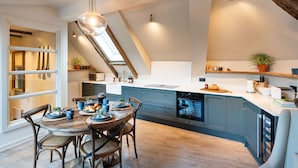 Eine moderne Küche mit Oberlicht, Esstisch aus Holz und blauen Schränken.