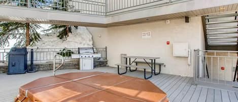 Eine Dachterrasse mit Whirlpool, Grill und Picknicktisch.