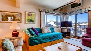 A cozy room with a bed, a sofa, a TV, and a window with a view. - Crested Butte Mountain Resort Properties by Vail (Crested Butte)