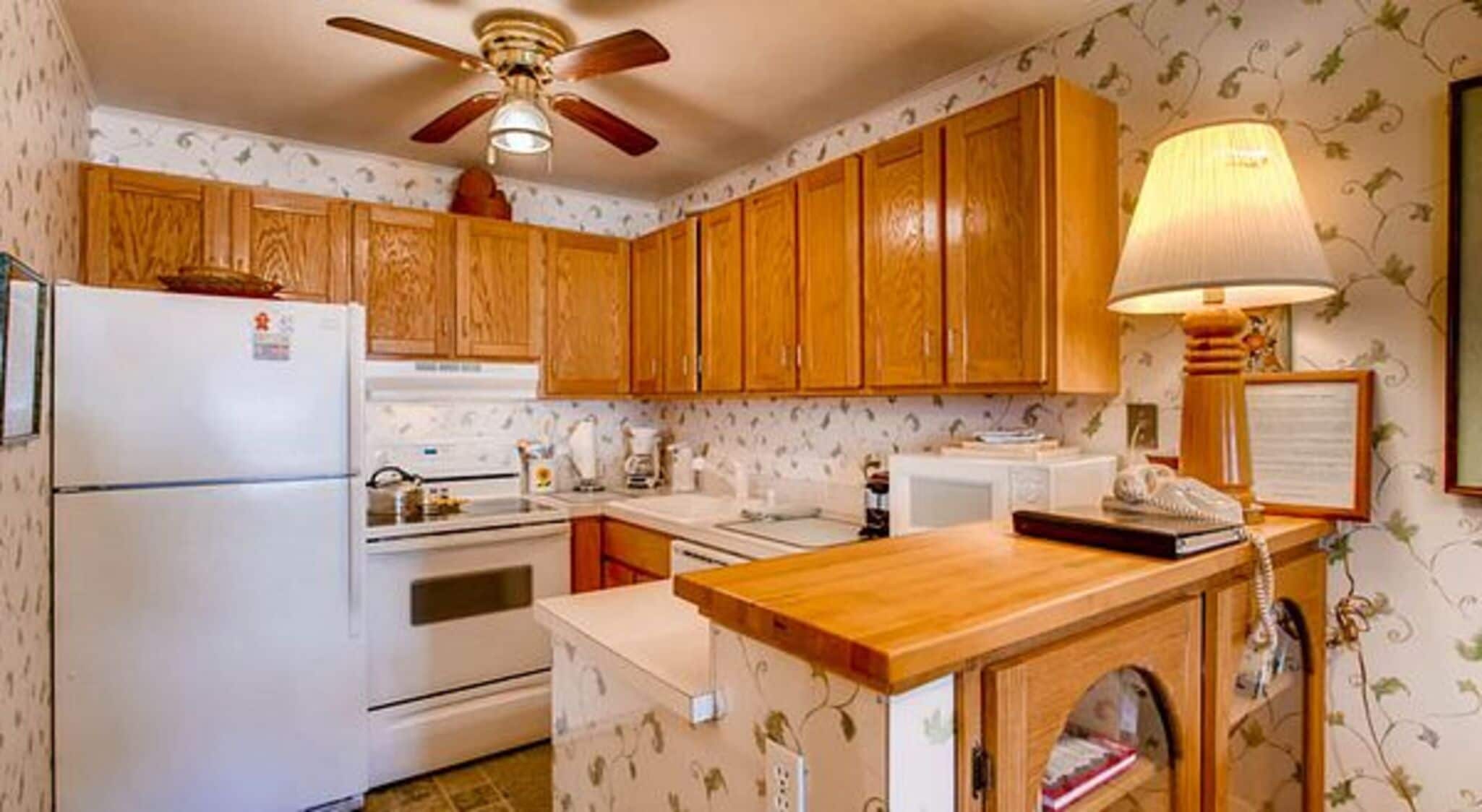 Una cocina compacta con armarios de madera, un refrigerador, una estufa y un lavamanos.