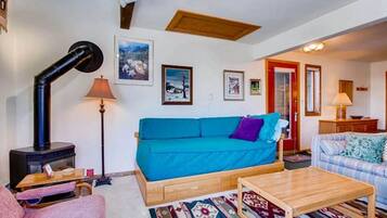A cozy living room with a blue sofa, a wooden coffee table, and a fireplace.