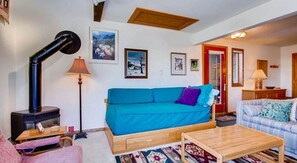 A cozy living room with a blue sofa, a wooden coffee table, and a fireplace. - Crested Butte Mountain Resort Properties by Vail (Crested Butte)