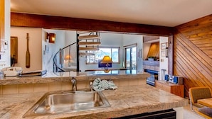 Una cocina con encimera de granito, pileta de acero inoxidable y una escalera en espiral que lleva a un nivel superior.