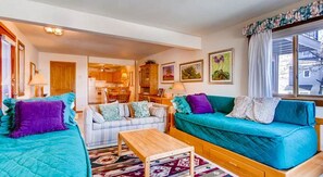 A cozy living room with a sofa set, a coffee table, and a kitchen area visible in the background. - Crested Butte Mountain Resort Properties by Vail (Crested Butte)