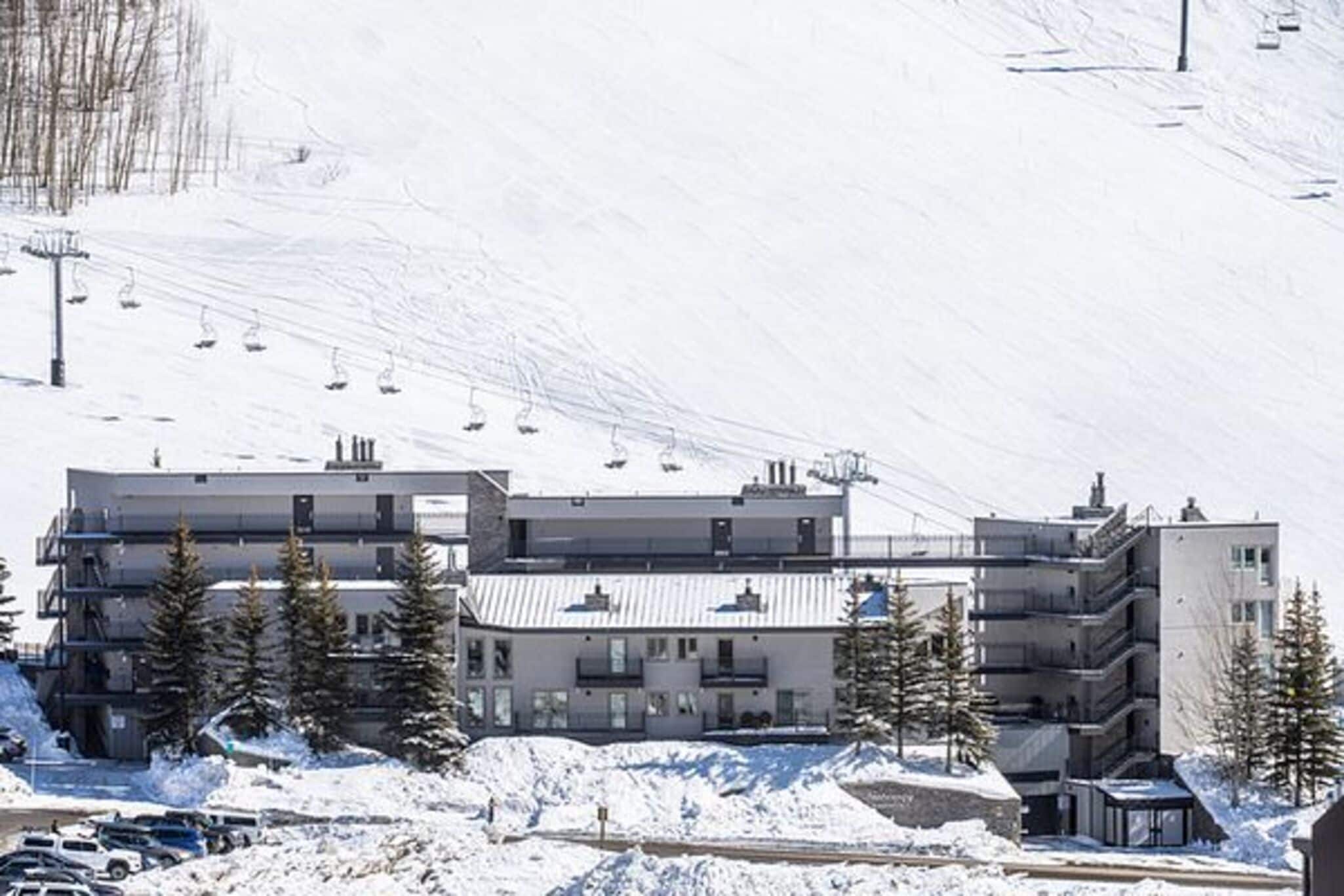 Un hôtel à plusieurs étages, avec un télésiège visible en arrière-plan.