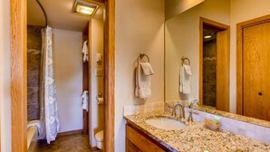 A bathroom with a shower, two sinks, and a large mirror. - Crested Butte Mountain Resort Properties by Vail (Crested Butte)