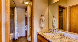 Une salle de bain avec une douche, deux lavabos et un grand miroir.