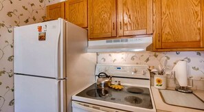 A kitchen with wooden cabinets, a white refrigerator, a stove, and a kettle on the stove. - Crested Butte Mountain Resort Properties by Vail (Crested Butte)