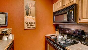 A kitchen with wooden cabinets, a stove, and a microwave.