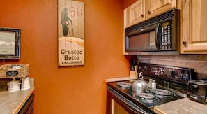 A kitchen with wooden cabinets, a stove, and a microwave. - Crested Butte Mountain Resort Properties by Vail (Crested Butte)
