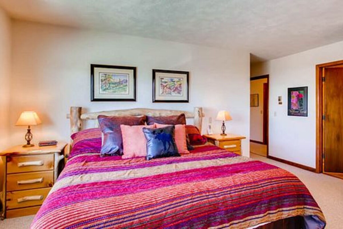 A bedroom with a large bed, two bedside tables, and two framed pictures on the wall.