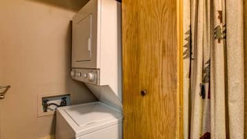 A laundry area with a washing machine and dryer, a wooden door, and a power outlet on the wall.