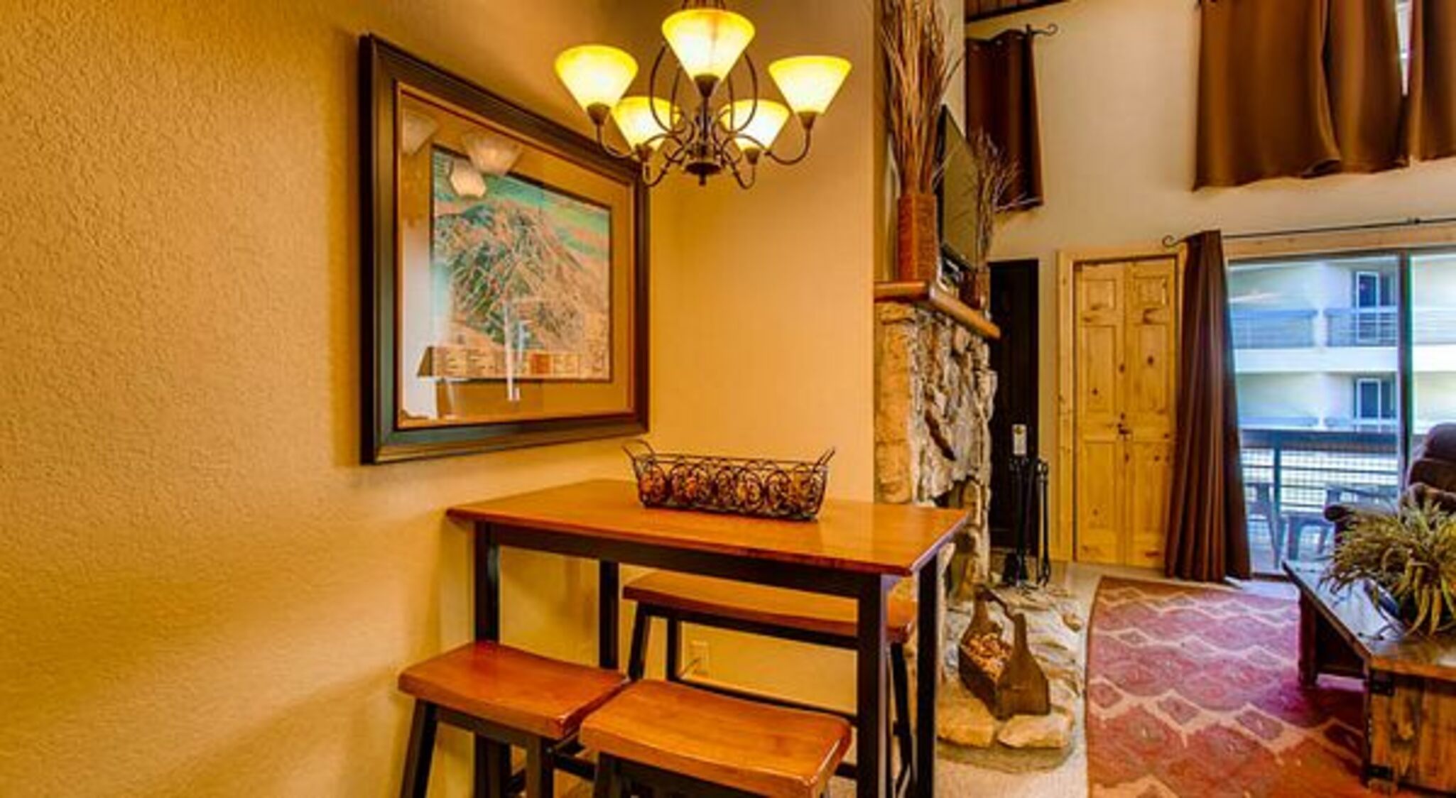 Une pièce chaleureuse avec une table en bois, deux chaises, un lustre et un mur en pierre.
