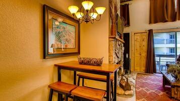 Une pièce chaleureuse avec une table en bois, deux chaises, un lustre et un mur en pierre.