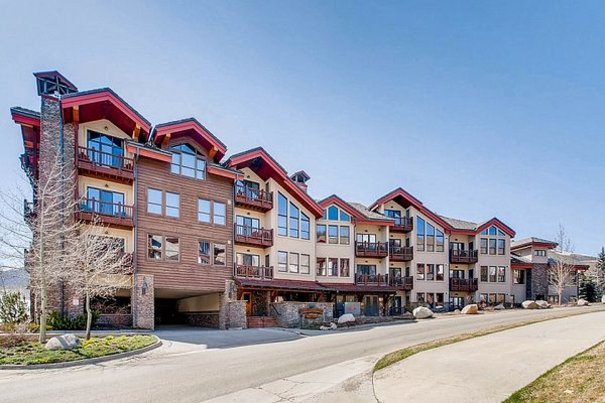 A row of multi-story buildings with balconies, a stone facade, and a clear sky.