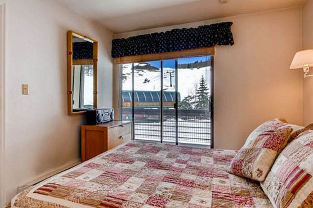 Un dormitorio con una cama grande, un aparador, un espejo y una ventana con vistas a un paisaje nevado.