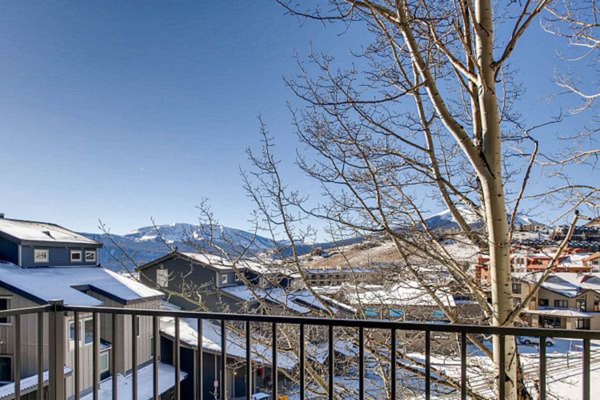 Una zona residencial cubierta de nieve, con casas y una montaña al fondo.