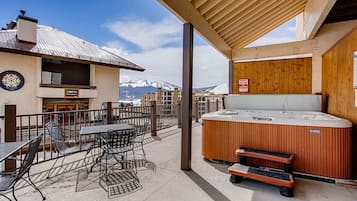 Un espacio al aire libre techado con un jacuzzi, mesas y sillas.