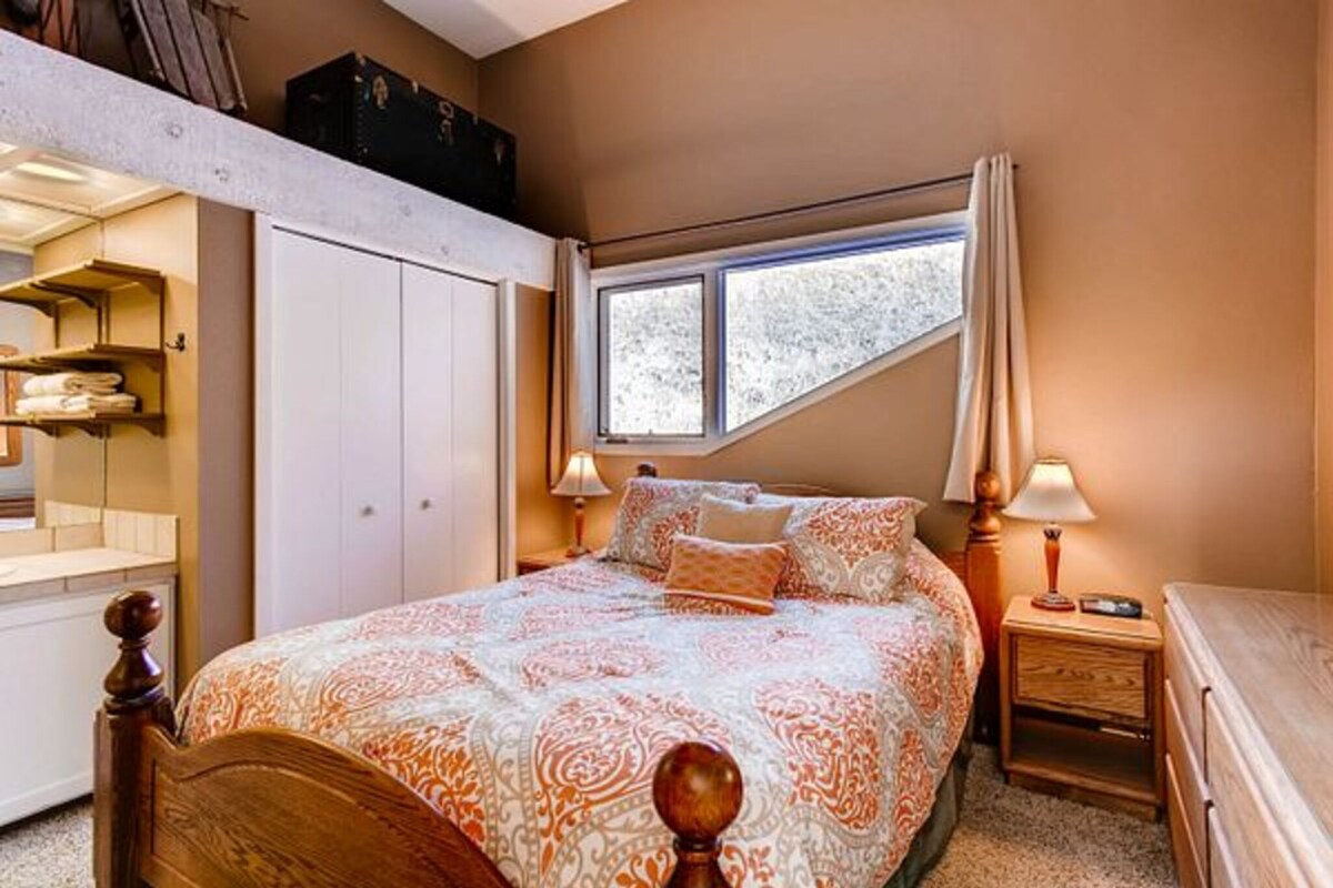 A bedroom with a bed, bedside tables, a window, and a wardrobe.