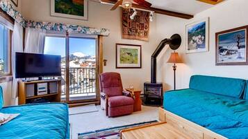 A room with a TV, a red chair, a blue sofa, and a wooden cabinet.
