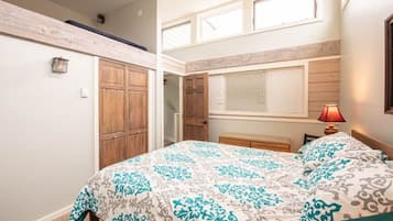 A bedroom with a bed, wooden wardrobe, and a window with blinds.