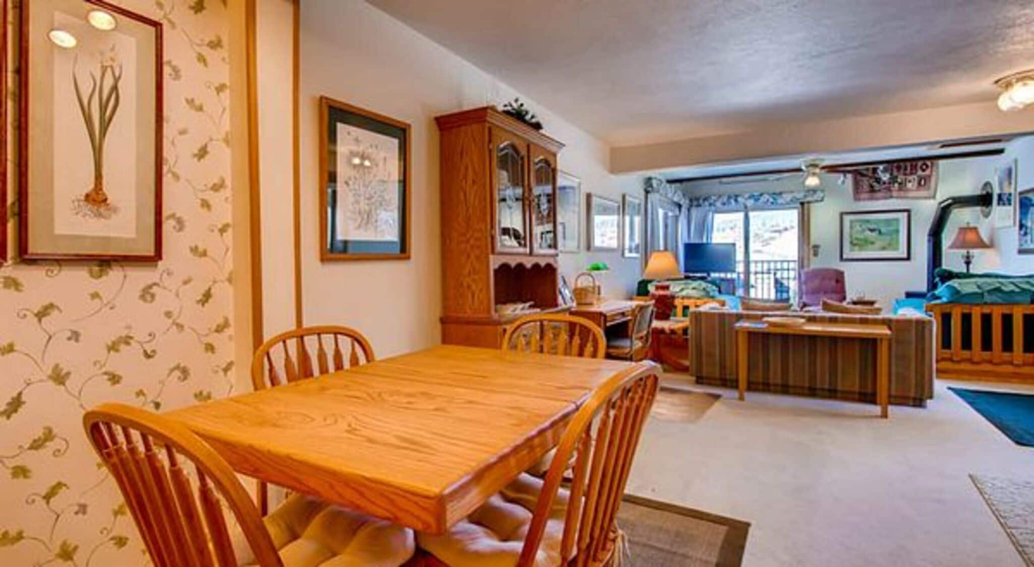 A cozy living room with a wooden dining table and chairs, a large cabinet, and a television.