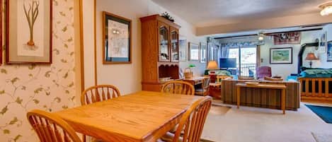 A cozy living room with a wooden dining table and chairs, a large cabinet, and a television.