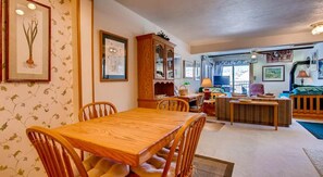 A cozy living room with a wooden dining table and chairs, a large cabinet, and a television. - Crested Butte Mountain Resort Properties by Vail (Crested Butte)