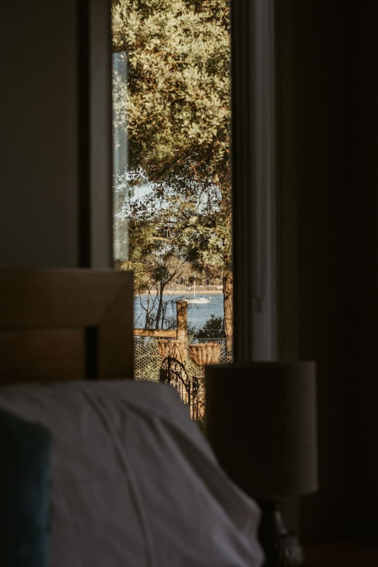 A bedroom with a view of a beach and a boat.